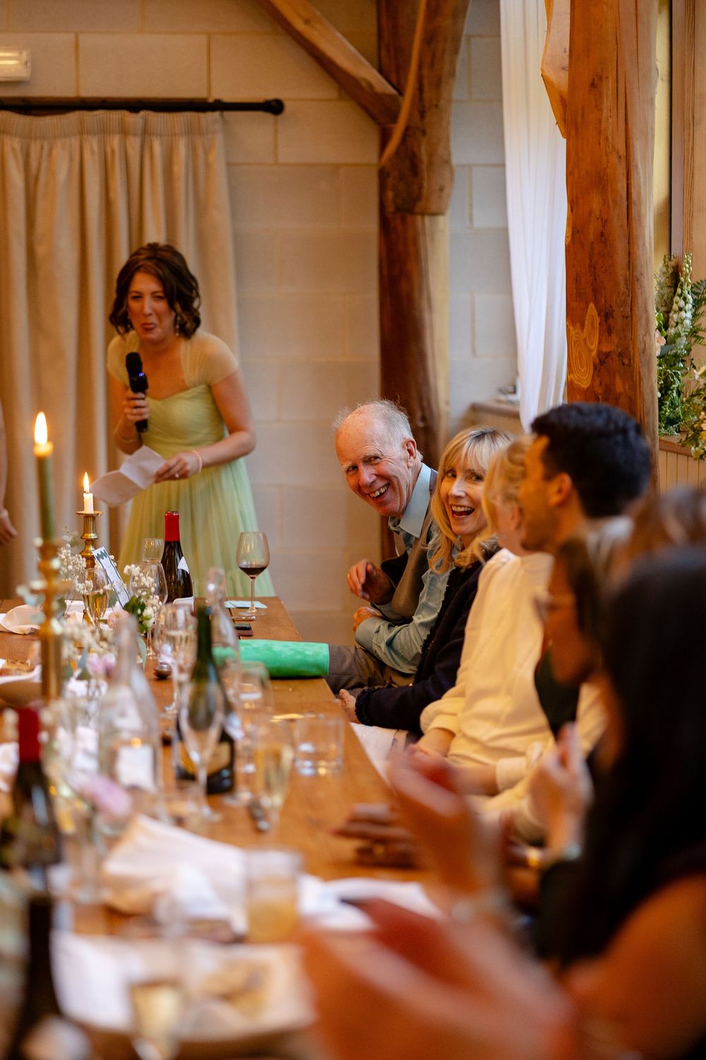 Wedding guests enjoying dinner and conversation at an elegant candlelit reception table with wine glasses and place settings.