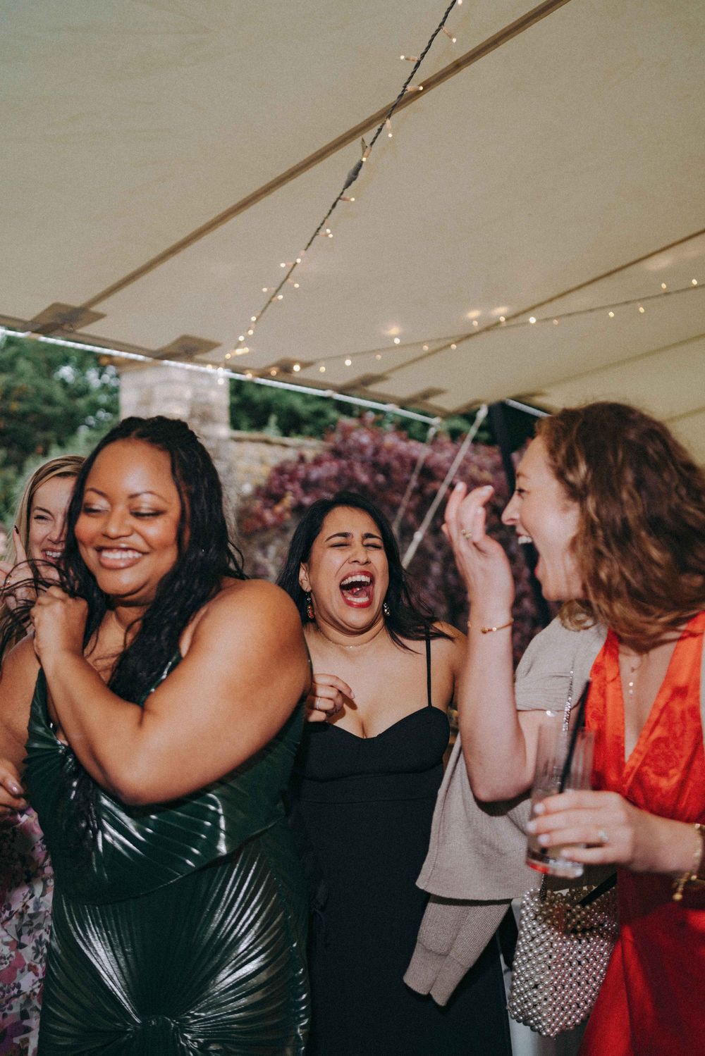 Group under the tent laughing, wedding cocktail hour