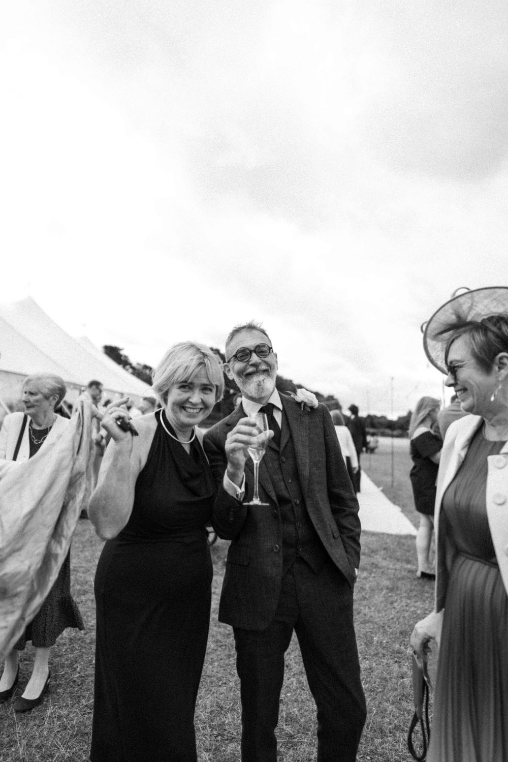 Group of friends  laughing beside a tent, wedding cocktail hour