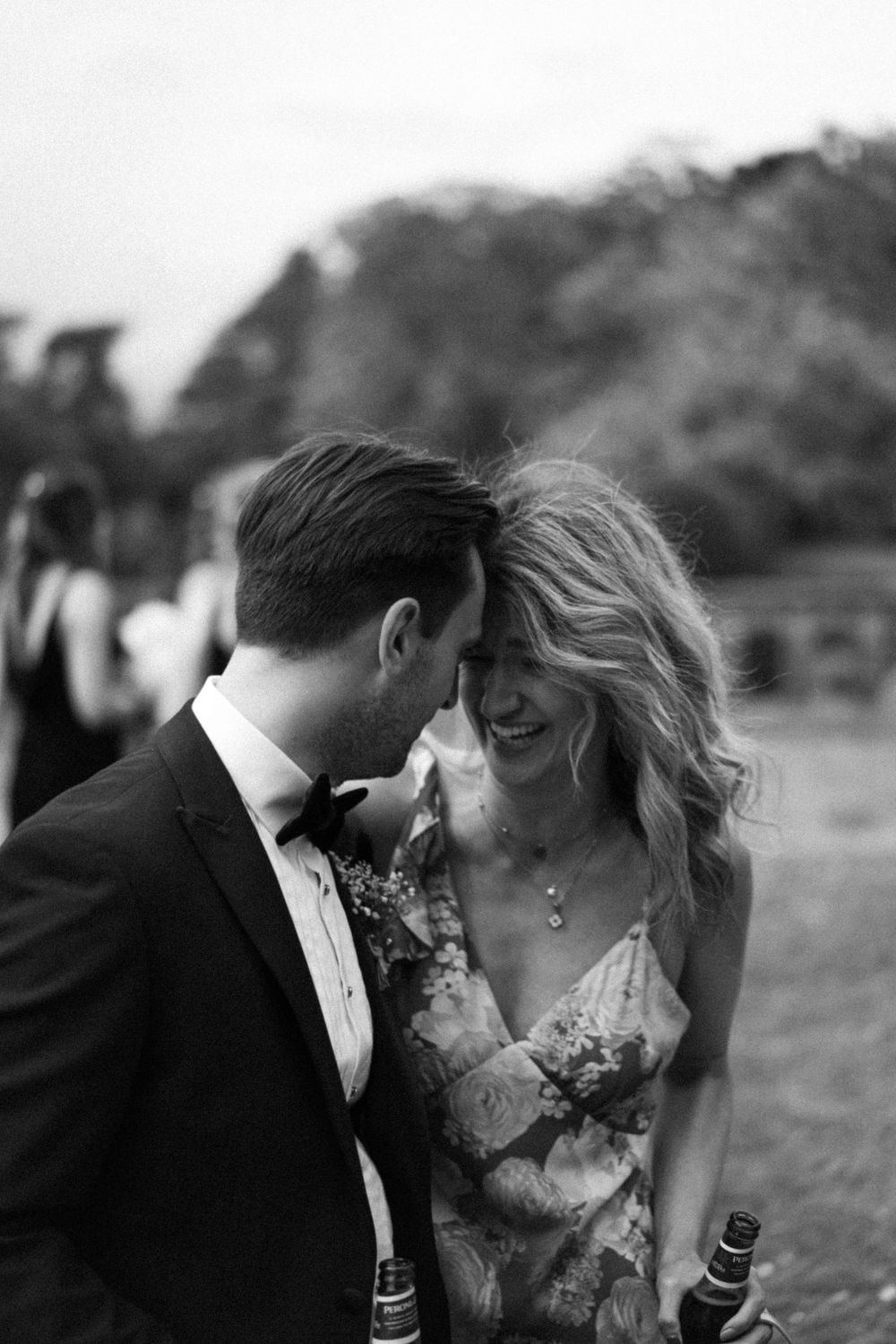 Two wedding guests lean heads together in a quiet, candid moment