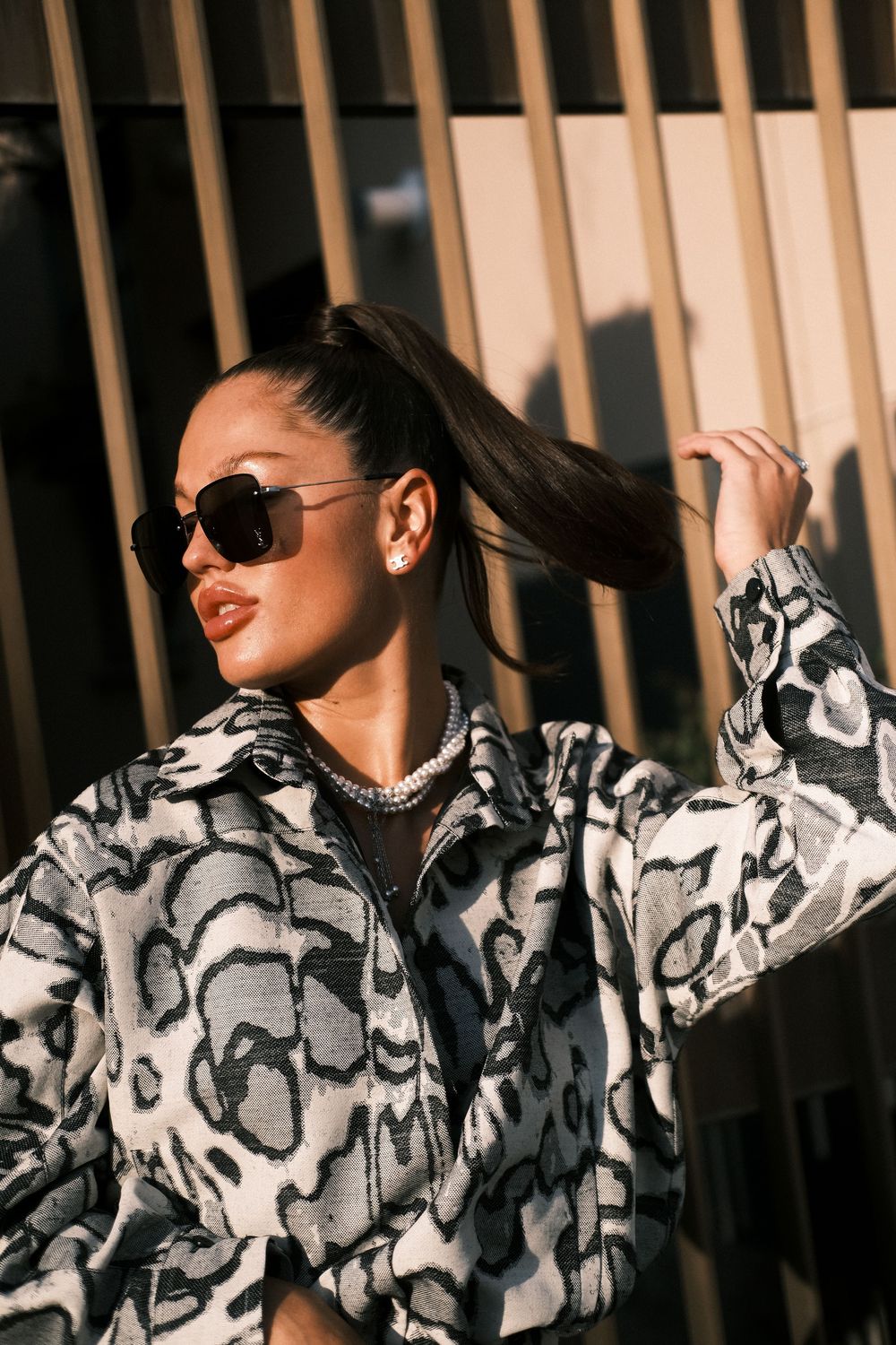 A fashion photo series showing a black and white patterned coat modeled against wooden slats in dramatic lighting.