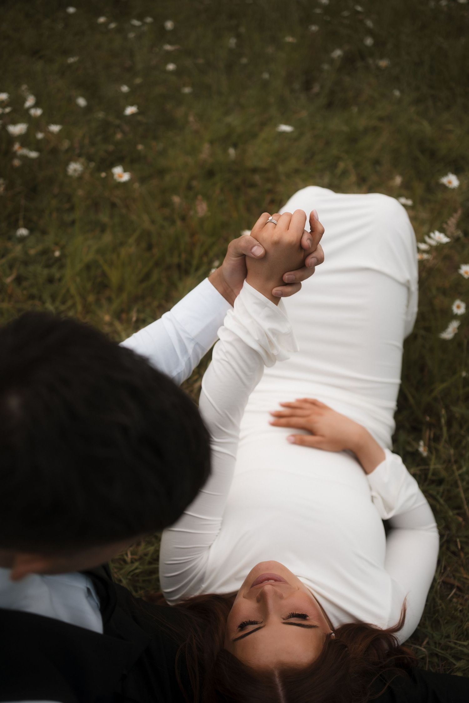A sequence of photos showing someone in a white shirt rolling on grass in an artistic motion.