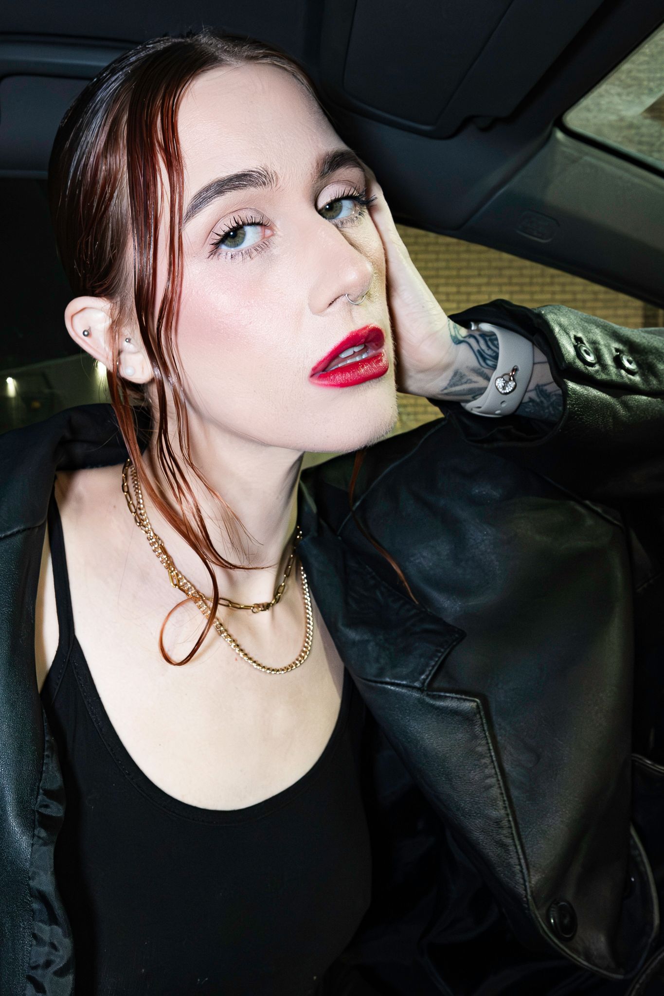 Stylish portrait taken inside car featuring gold chain necklace and leather jacket.