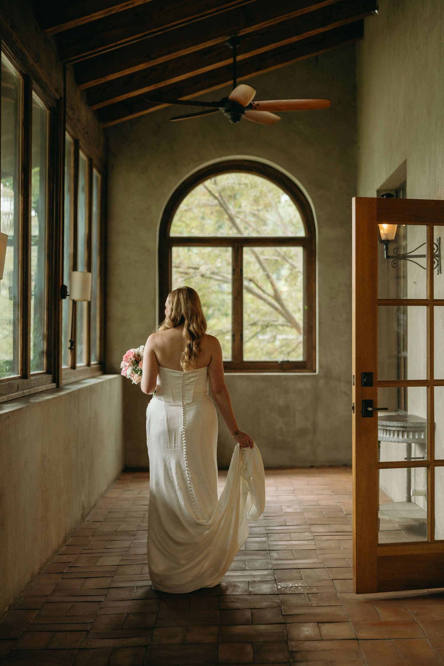 Bride walking and looking out of glass windows during bridal portraits at Summerour Studio wedding venue in Atlanta, Georgia