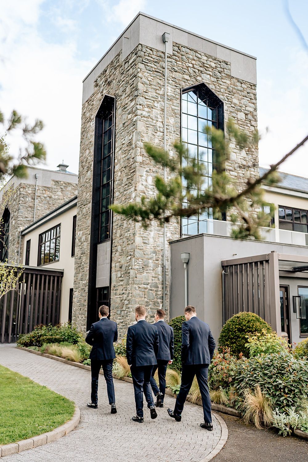 A series of five connected photos showing people walking along a stone exterior building with modern architectural details.