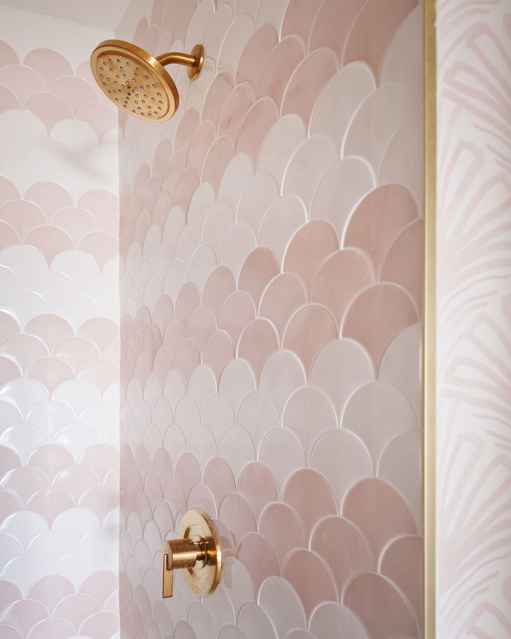 Pink ombre fish scale shower tiles with gold fixtures and a rain showerhead in a luxury bathroom.