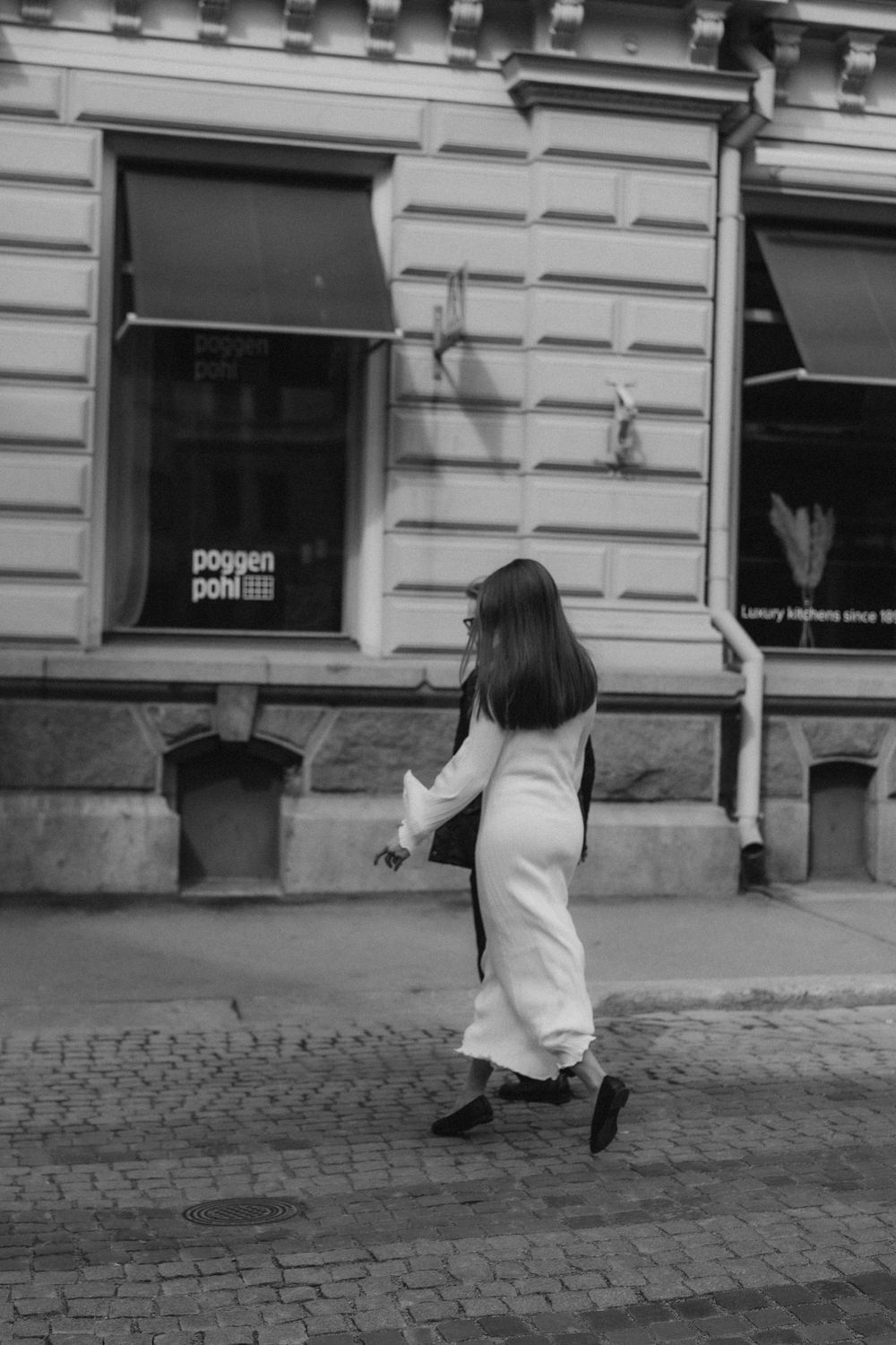 Engaged couple walking hand in hand through Helsinki city centre during a cinematic engagement session