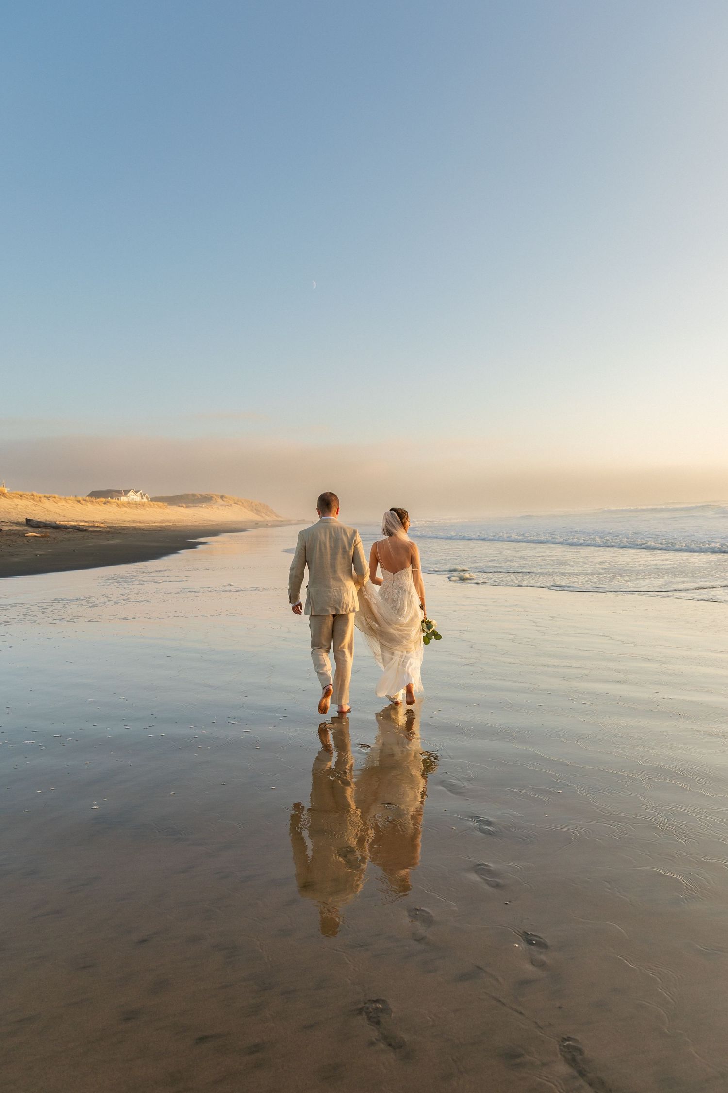 Newlywed couple walking hand in hand on a beach in coastal North Carolina after their elopement