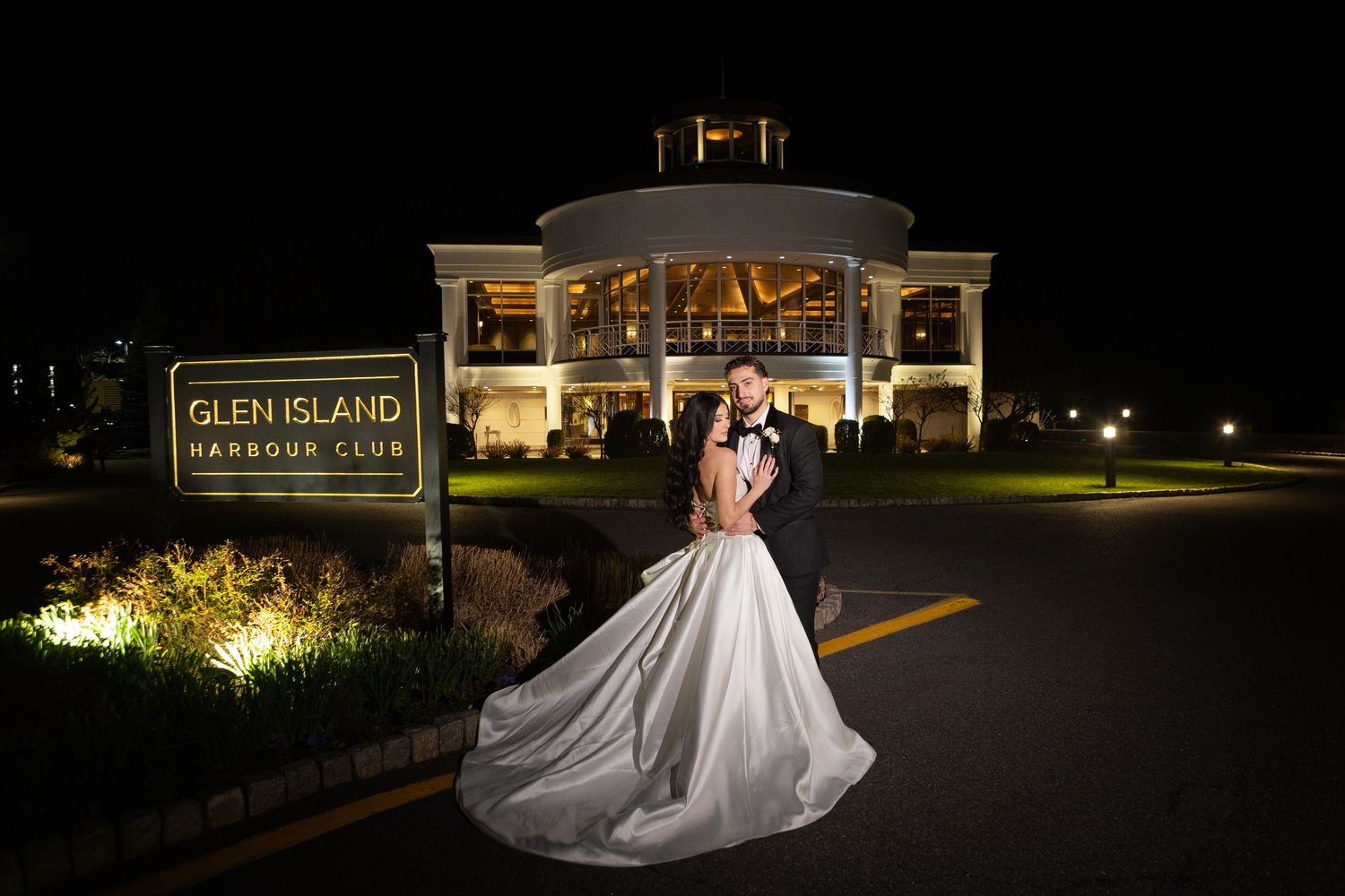 Glen Island Harbour Club Wedding Photographer. Bride and groom posing in front of the illuminated Glen Island Harbour Club during a luxury W