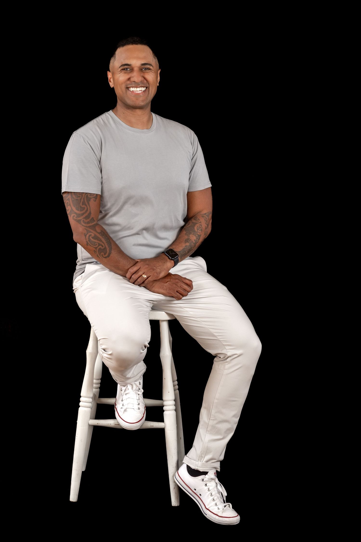 Professional branding portrait of Maori man sitting. Black backdrop, arms crossed, smiling. Catherine Lundin. Branding portrait photography