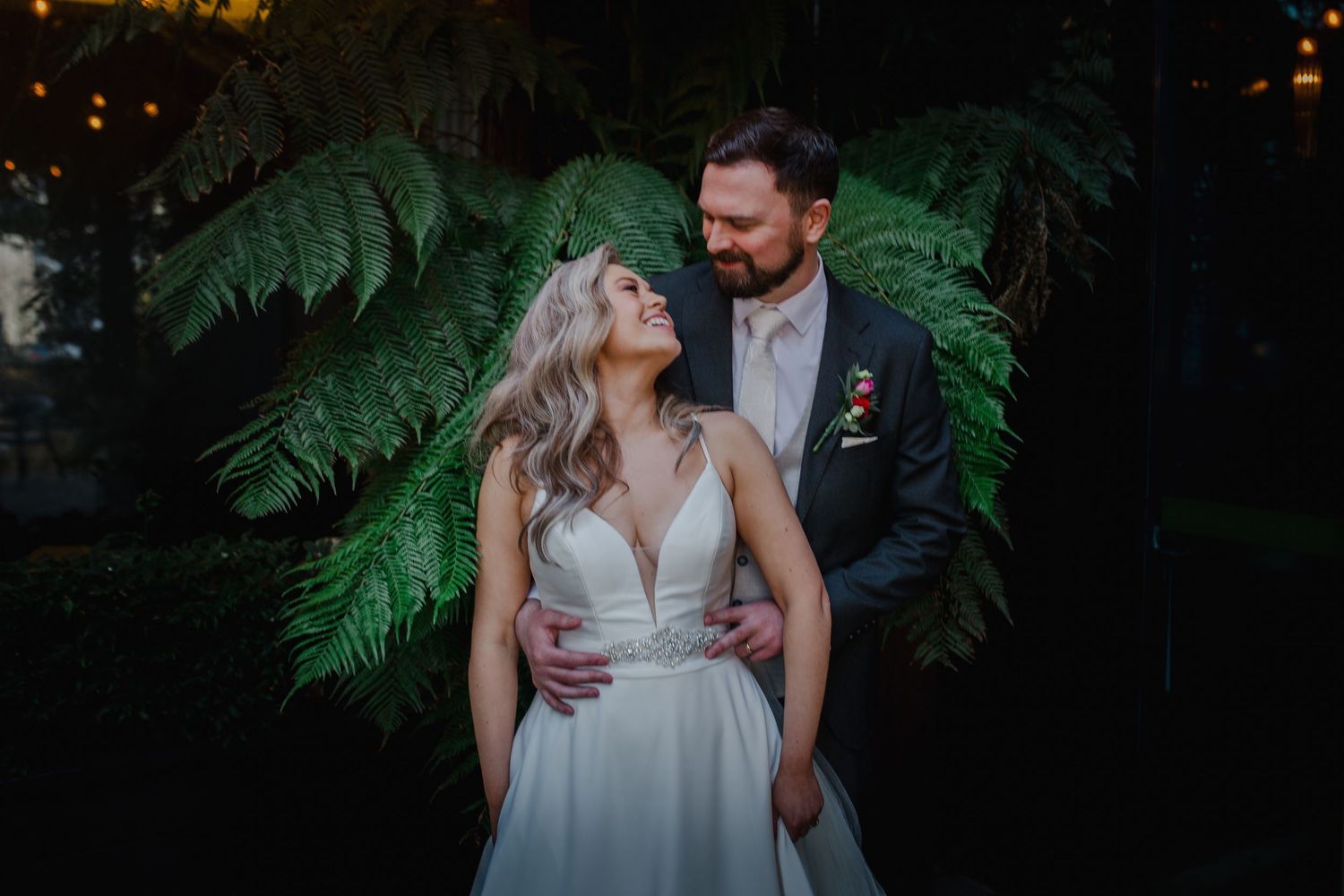 Bride with red updo hairstyle adorned with crystal hair vine, styled by hairdresser on wedding day.