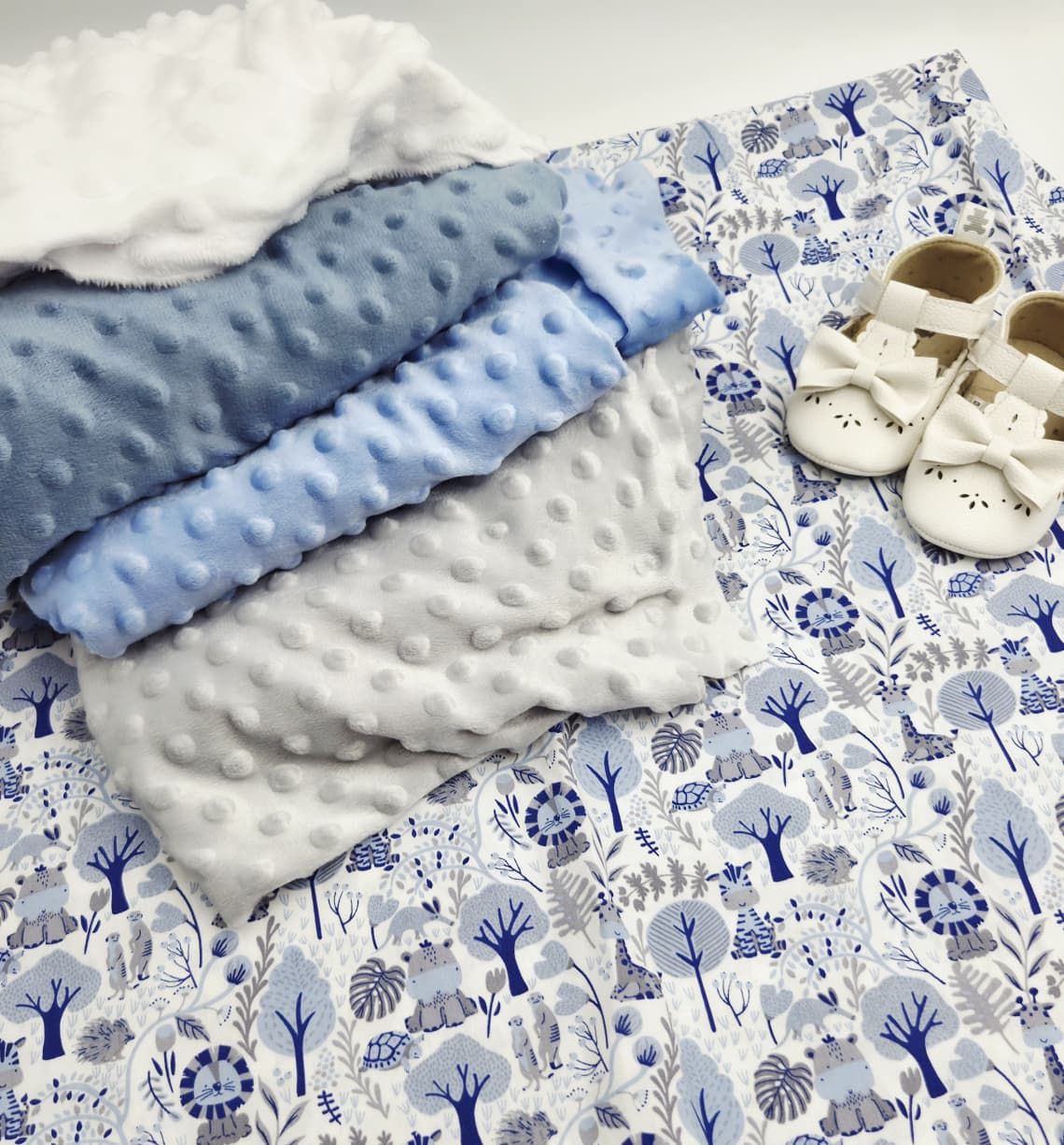 Blue and white baby blanket set with minky dot fabric and floral print, displayed with white baby shoes.
