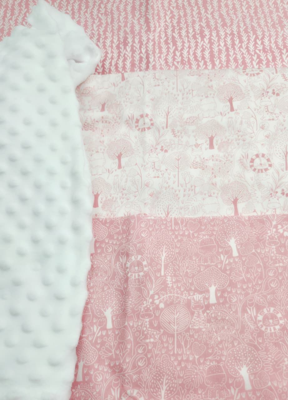Pink woodland animal print patchwork baby quilt with white minky dot fabric detail.