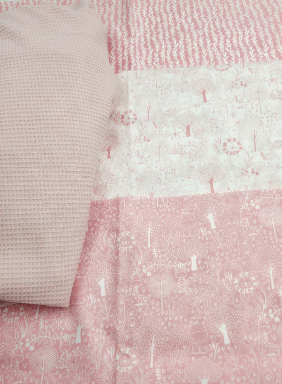 Pink patchwork quilt with floral and woodland animal prints, featuring soft pastel tones and waffle texture fabric.