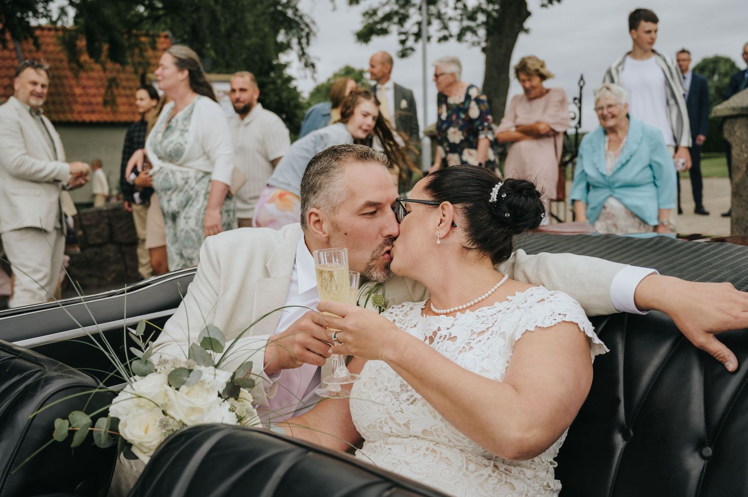 Bride and groom share a romantic kiss on a navy blue velvet sofa in an elegant, art-decorated venue lounge.