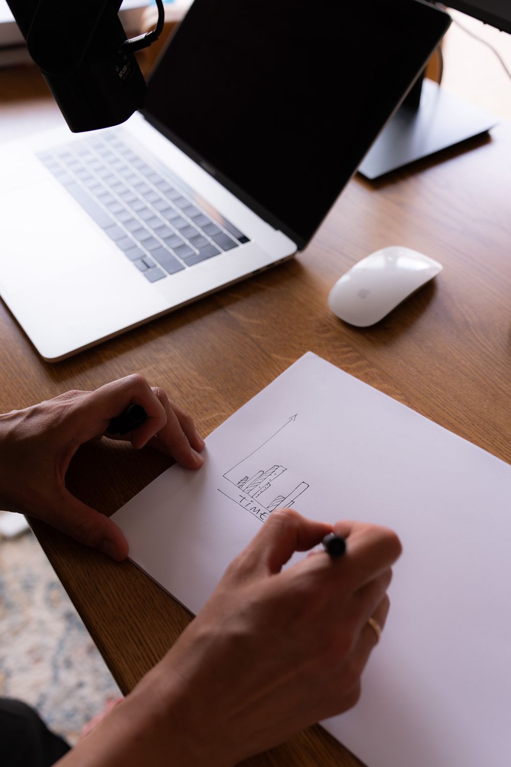 Table with laptop and hands writing