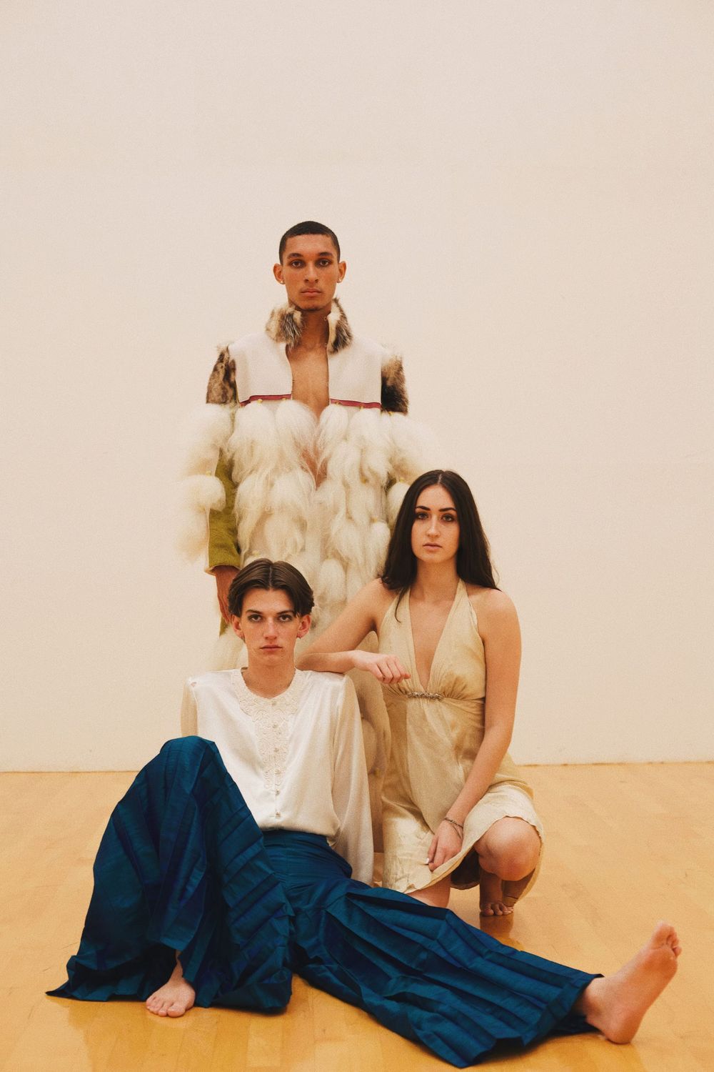 Modern fashion portrait of three models in neutral tones against a beige backdrop.