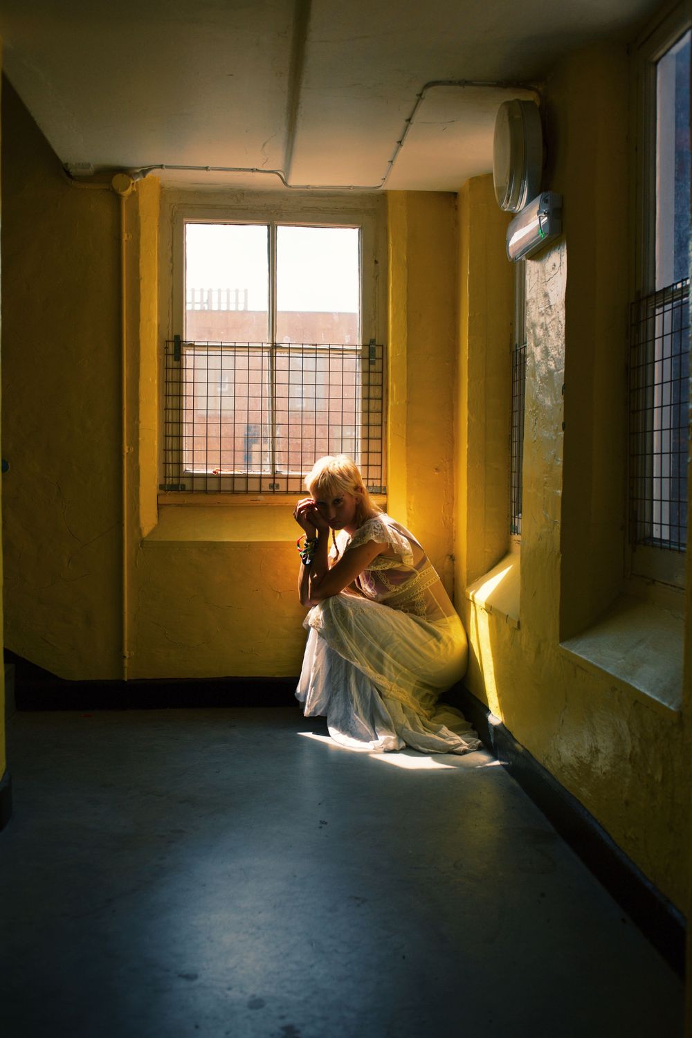 Atmospheric portrait of a figure in flowing dress caught in dramatic window light.