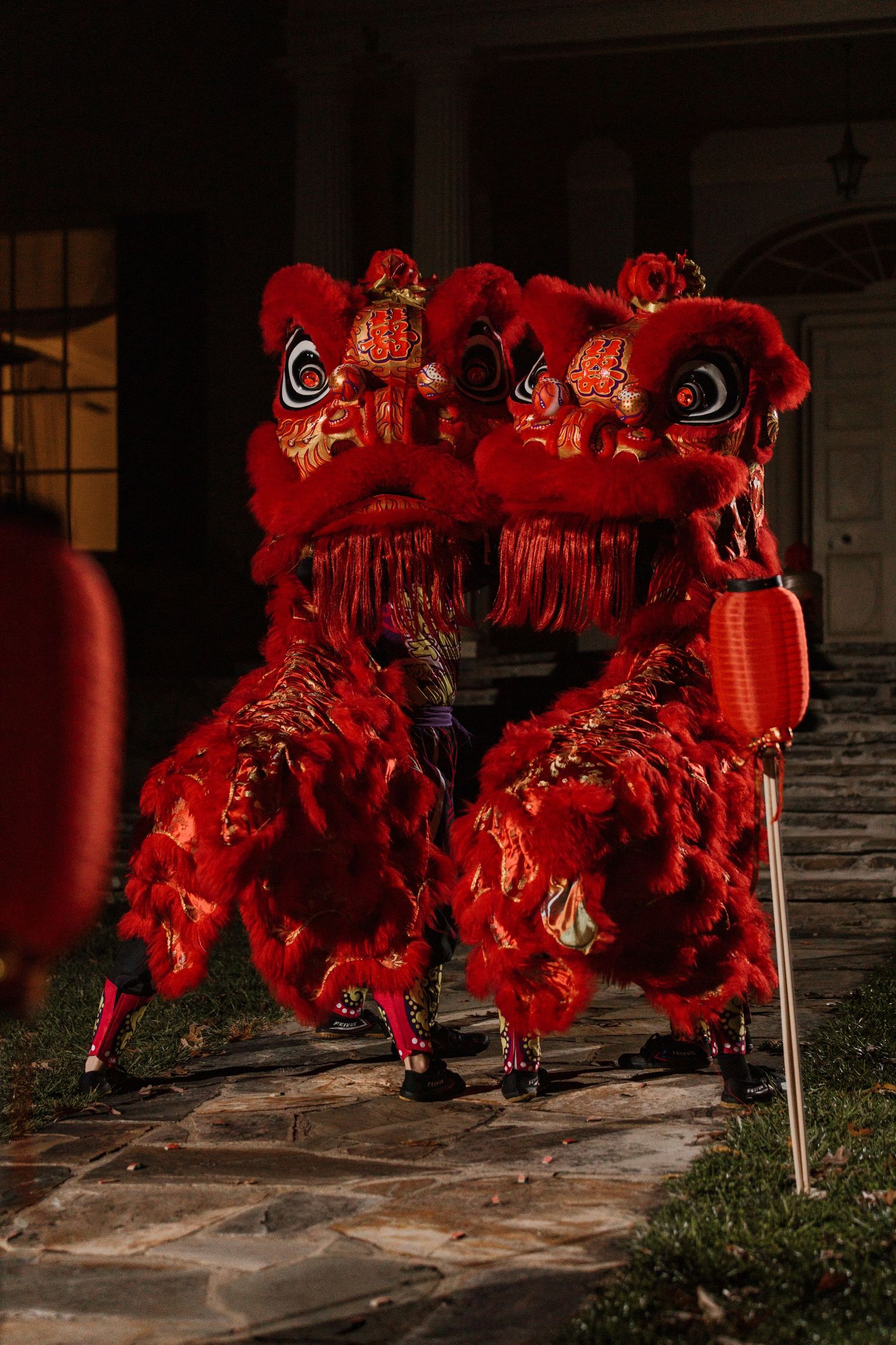 Traditional Chinese lion dance performers in bright red costumes performing at night at Rust Manor House, Virginia.