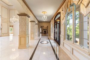 Elegant interior hallway with crystal chandeliers and marble flooring in a luxury estate.