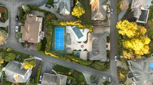 Aerial view of residential neighborhood with autumn trees and winding streets.
