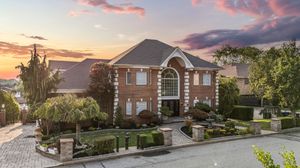 Panoramic view of luxury home exterior with dramatic sunset sky.