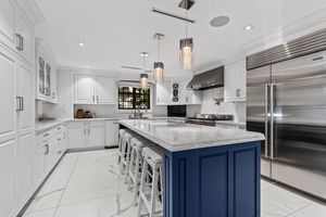 Pristine white kitchen with navy blue island and high-end stainless steel appliances.