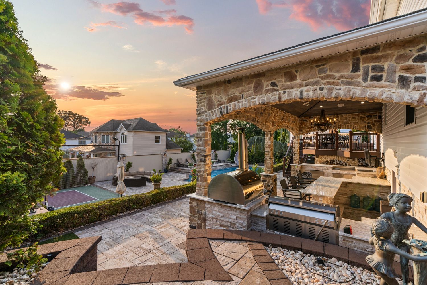 Upscale outdoor kitchen and entertainment area with stone counters and stainless steel appliances.