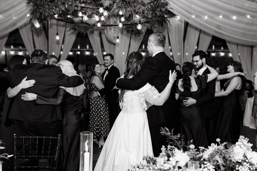Wedding reception venue decorated with string lights and white fabric draping from ceiling.