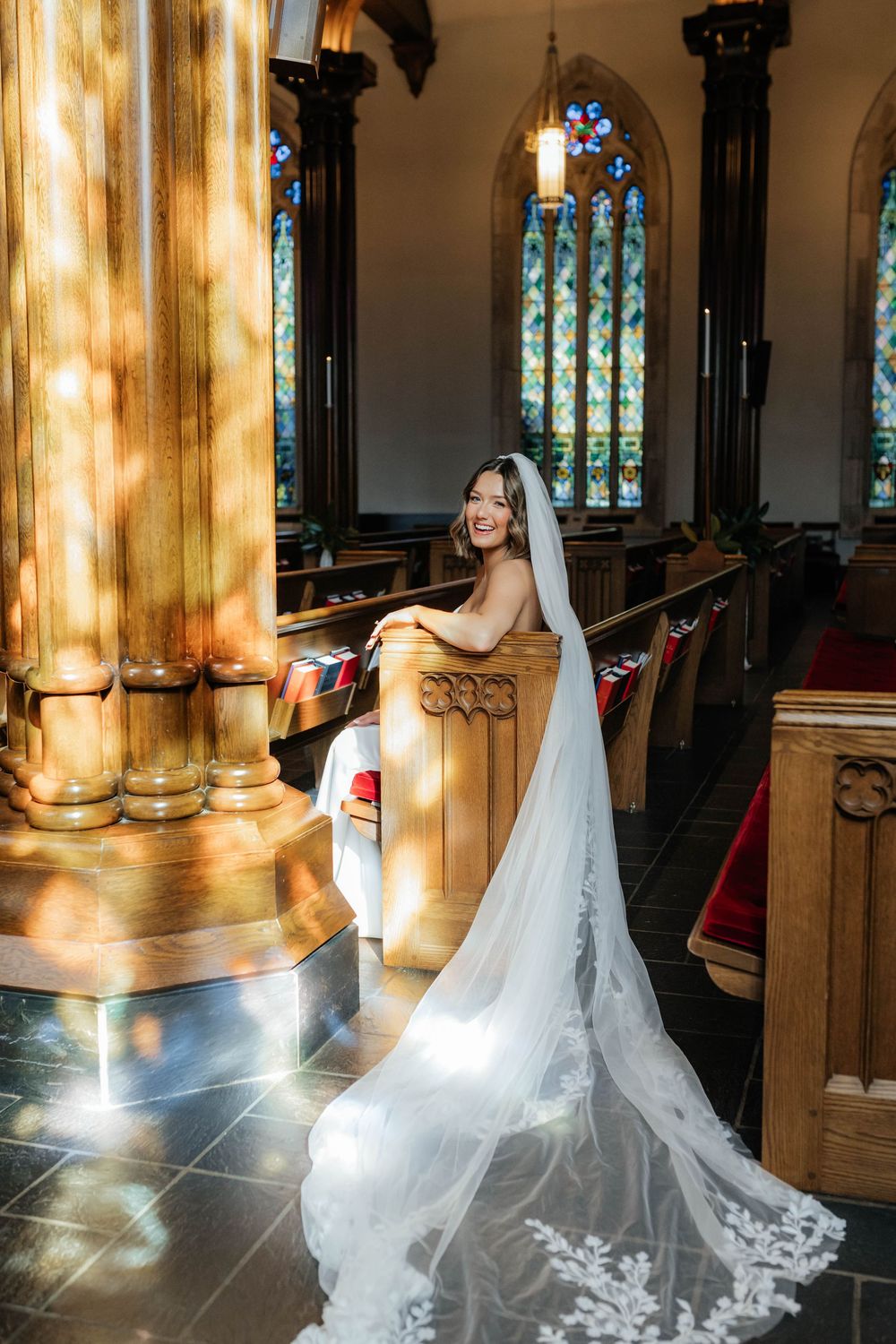 Dramatic bridal portraits in a church with golden sunlight streaming through stained glass windows.