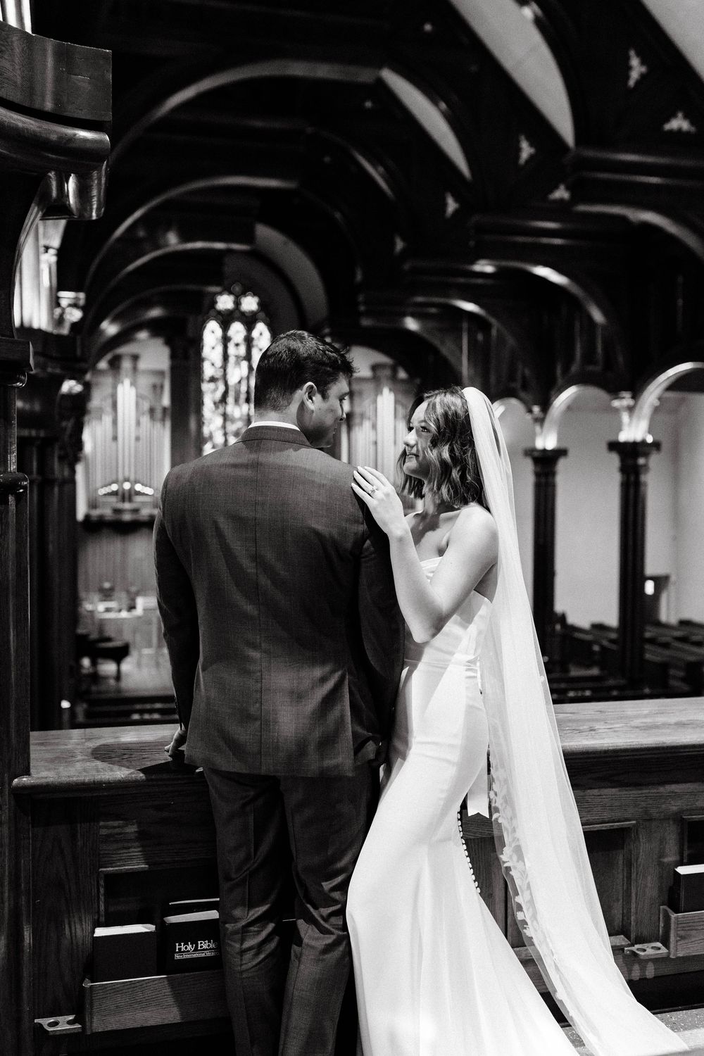 Black and white wedding photos in church with dramatic architectural details.