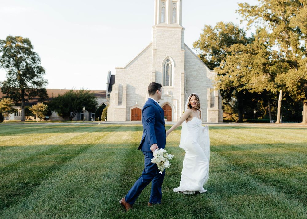 Wedding couple shares candid moments on church lawn during sunset.