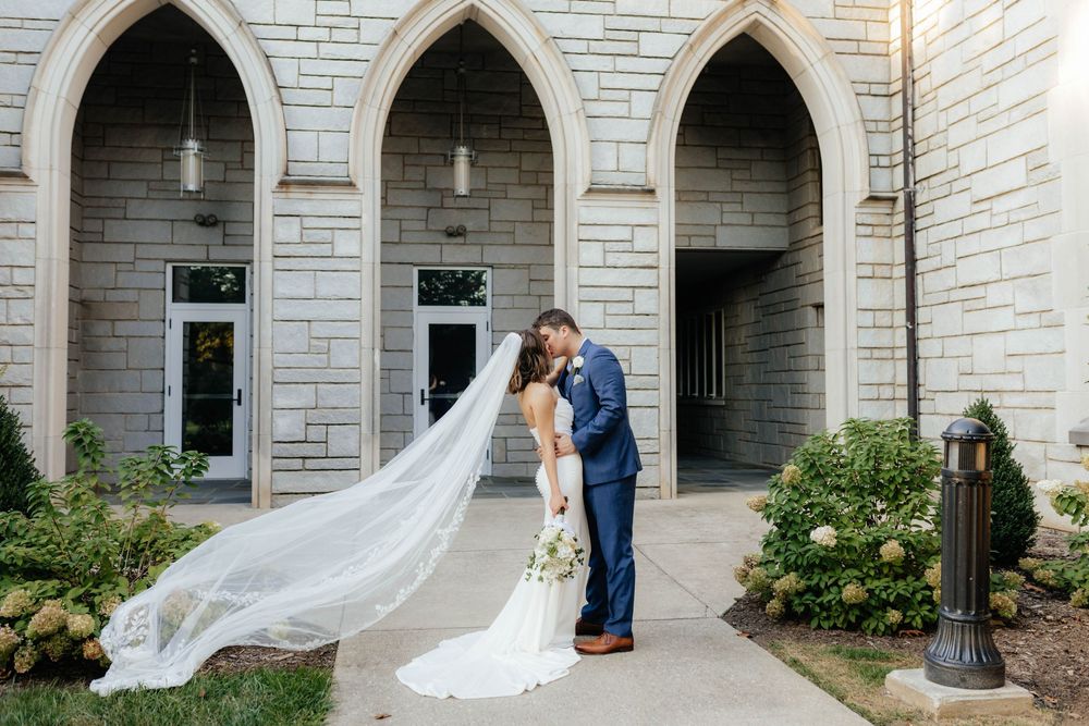 Wedding portraits taken along stone archways of church exterior.