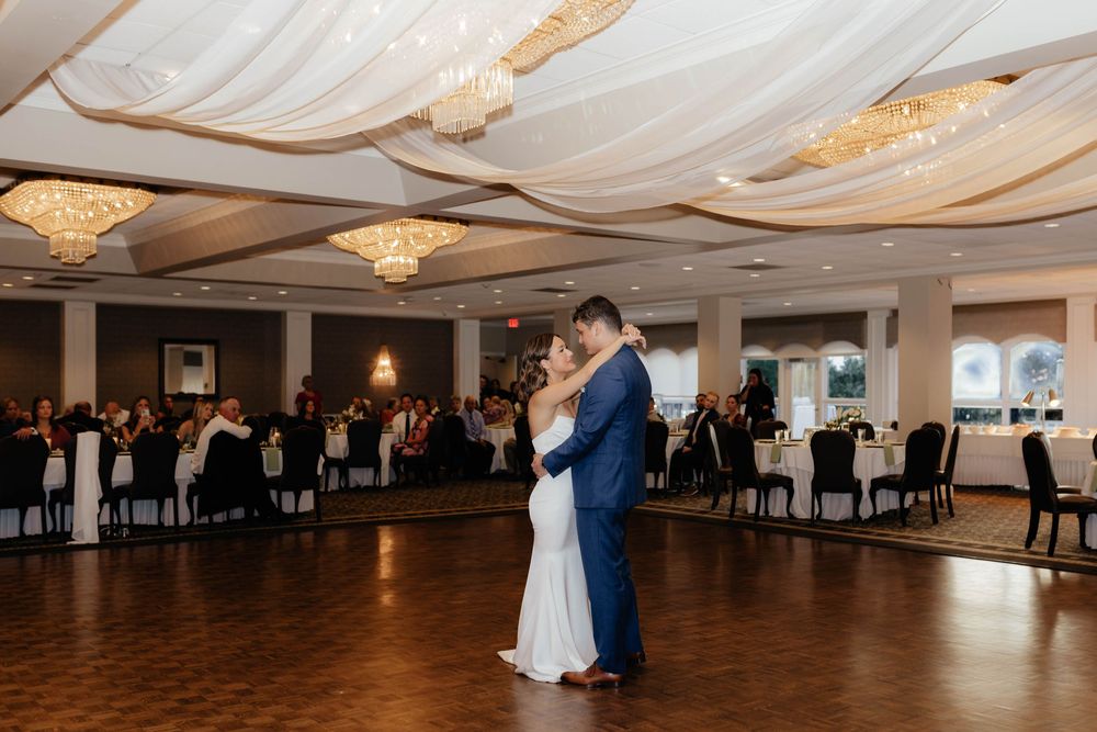 First dance in an elegant ballroom with draped fabric ceiling and chandeliers.