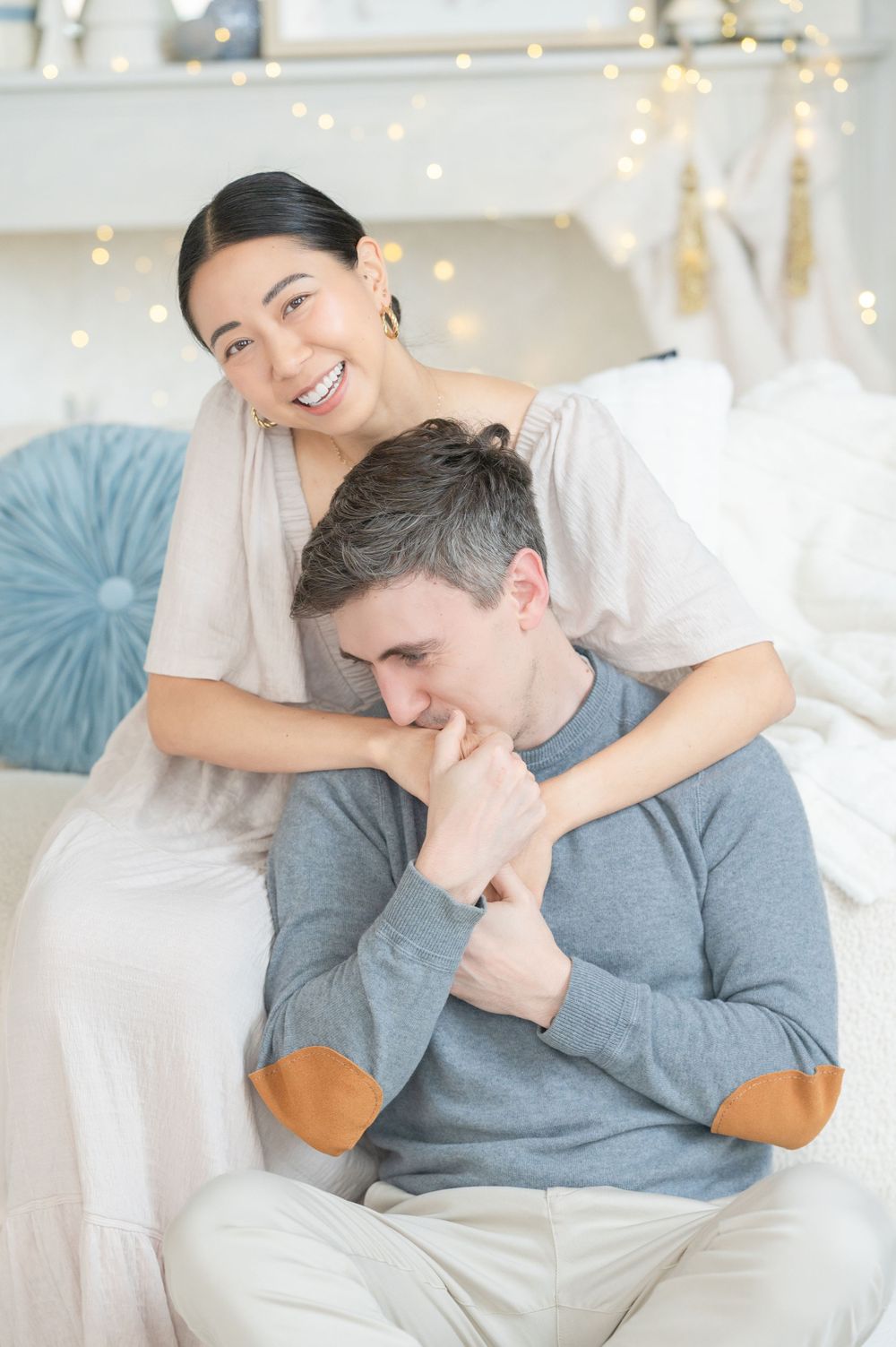 A tender moment shared between a couple on a white couch with holiday decorations in the background.