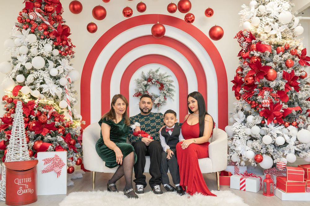 Family holiday photo with red and white candy cane striped backdrop and Christmas decorations.