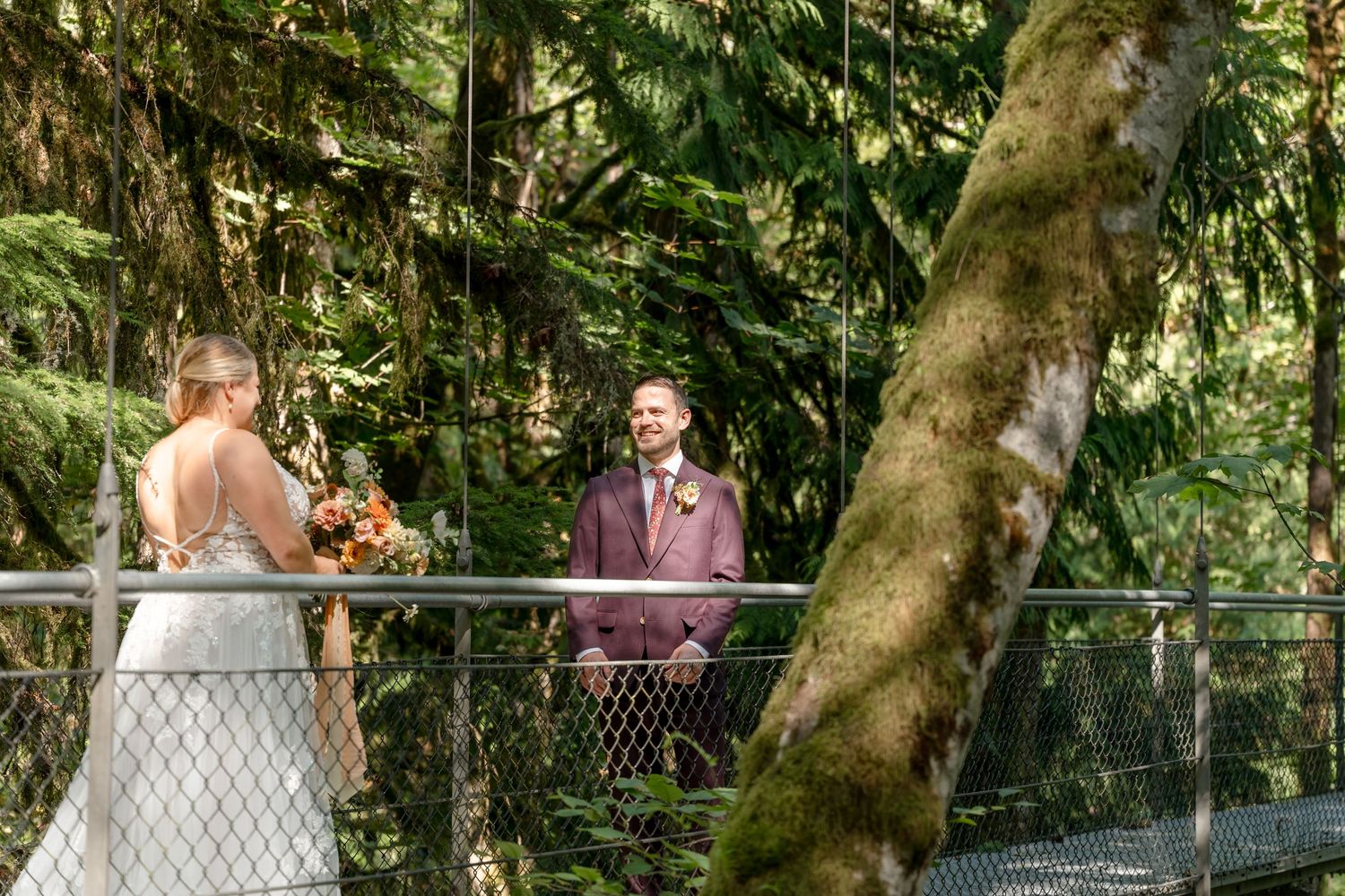 Wedding ceremony taking place on a scenic suspension bridge surrounded by lush forest greenery.