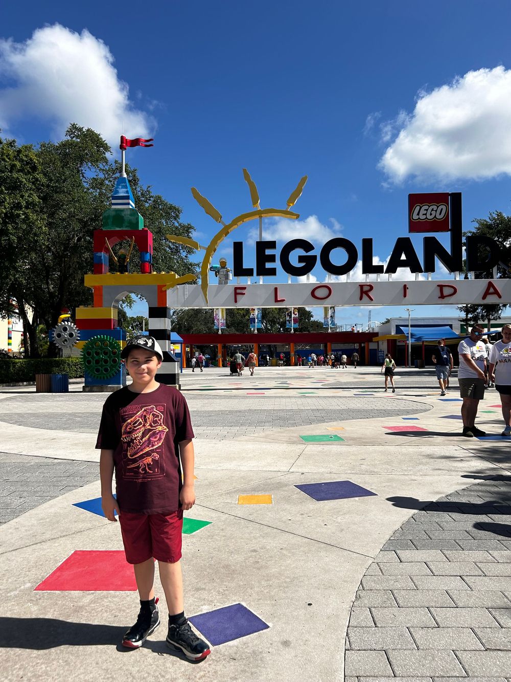 Colorful LEGOLAND Florida entrance sign with vibrant square patterns on the ground and fluffy white clouds in the sky.