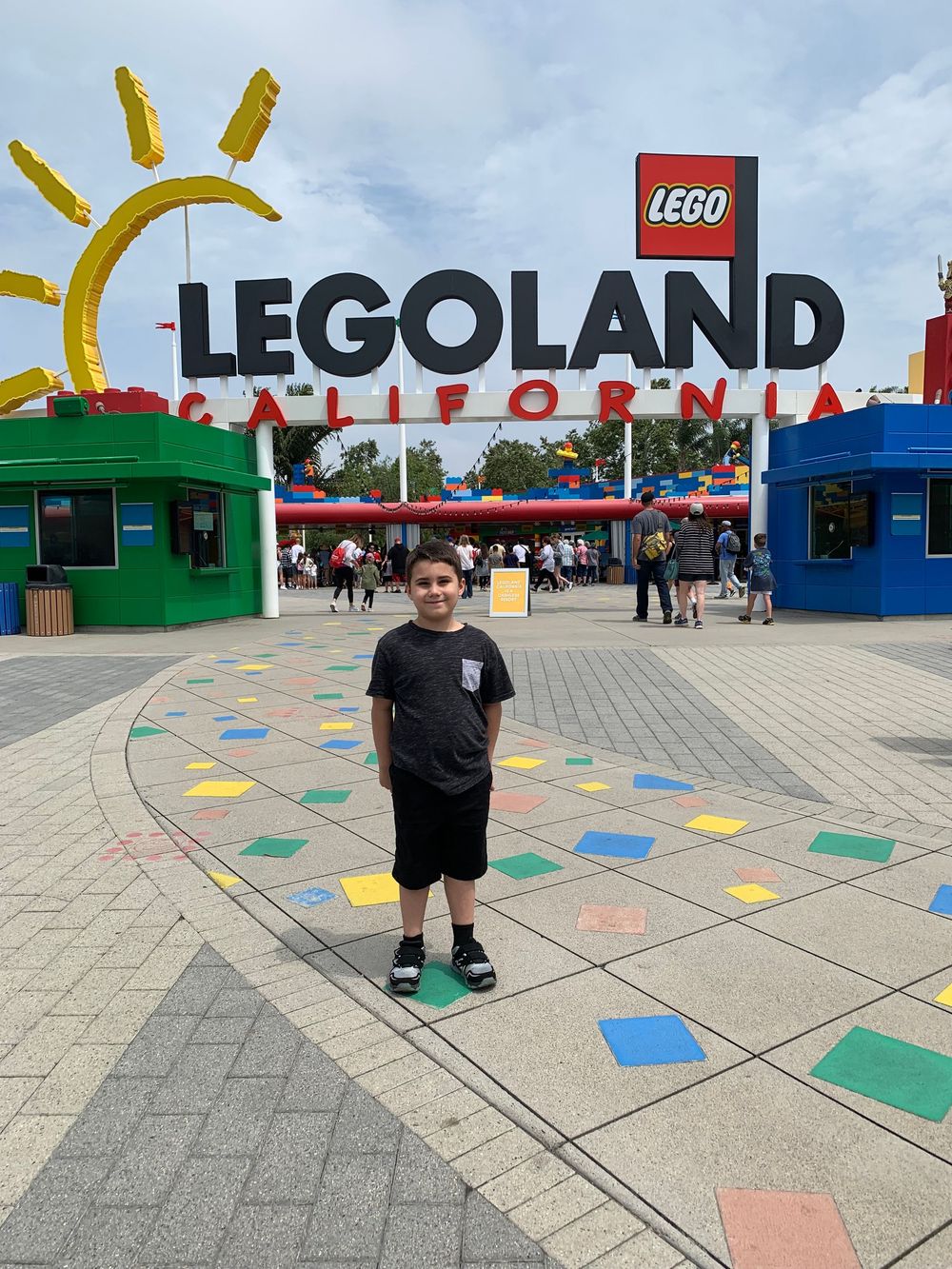 Colorful entrance to Legoland California theme park with decorative geometric shapes on the ground and sunny logo sign.