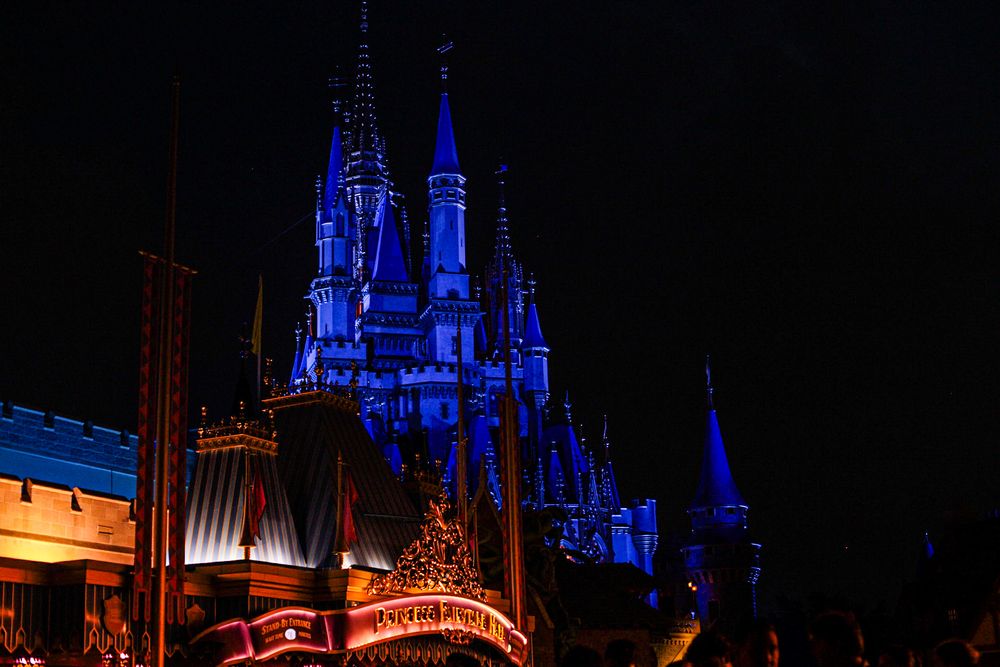 Cinderella Castle illuminated in blue lights against the night sky at Disney World.
