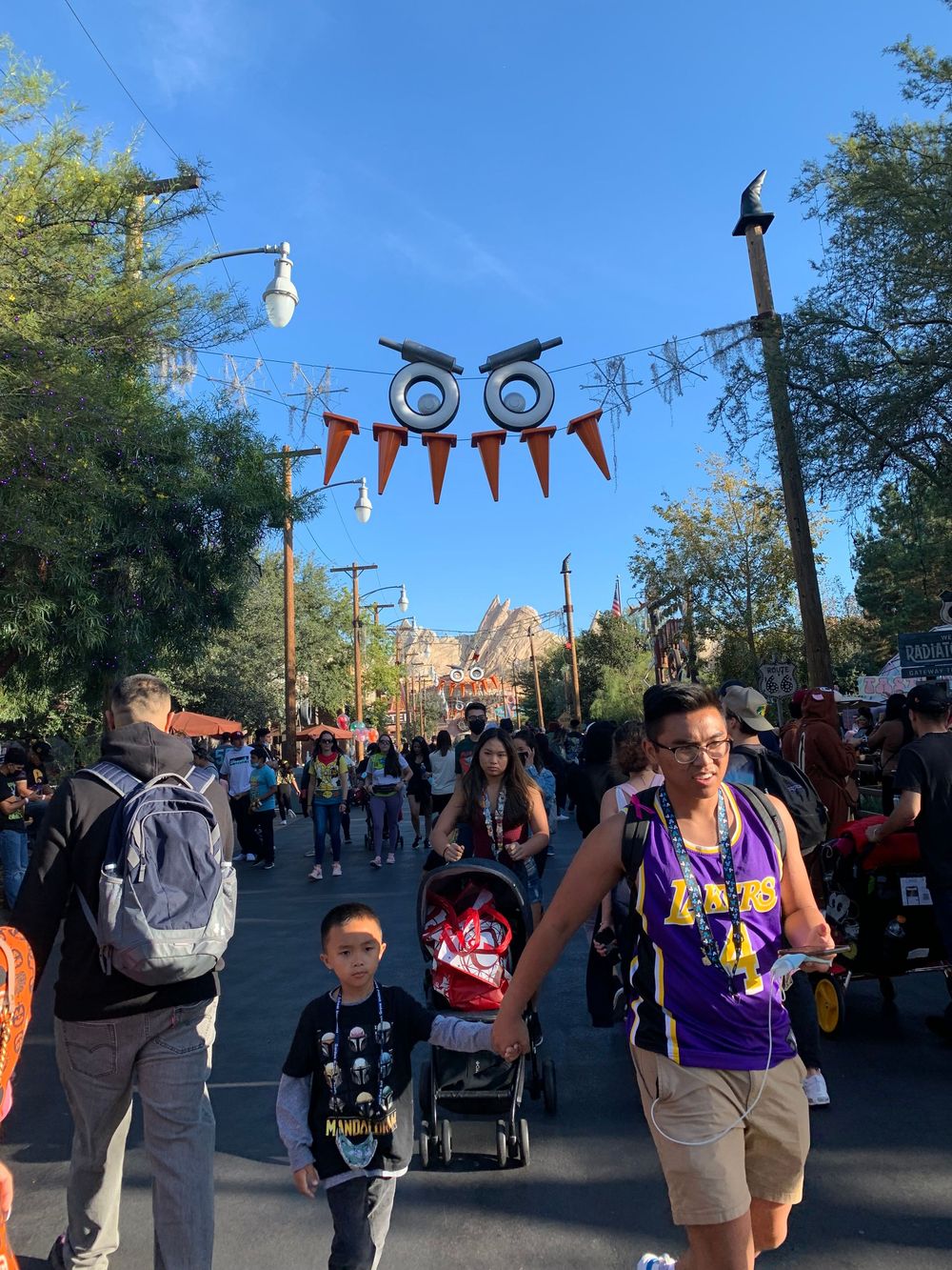 Halloween decorations and festive banners hang over a crowded walkway at Disney California Adventure theme park.