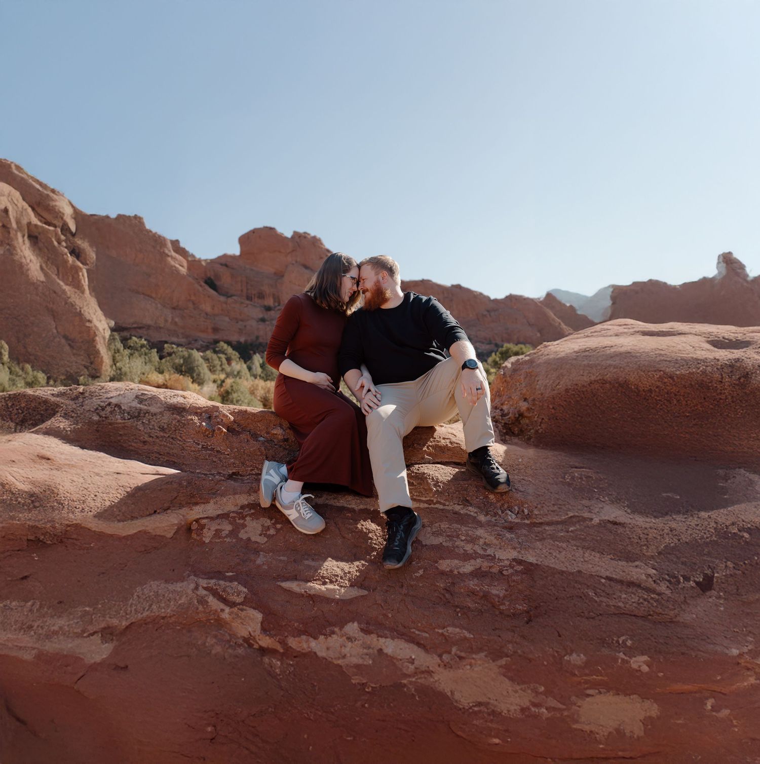 A couple shares a joyful candid moment together outdoors in casual sweaters during golden hour.