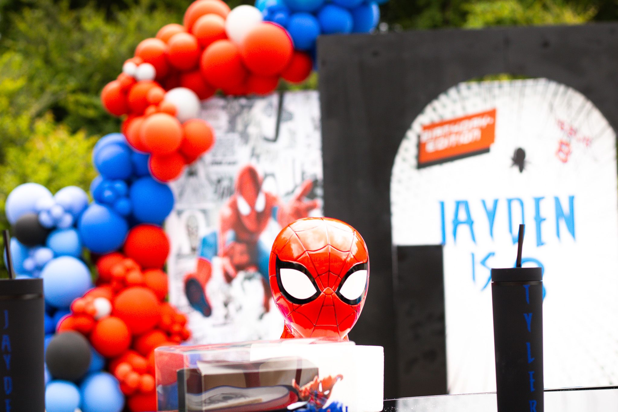 Spider-Man themed party display with red and blue balloon garland and decorative backdrop.