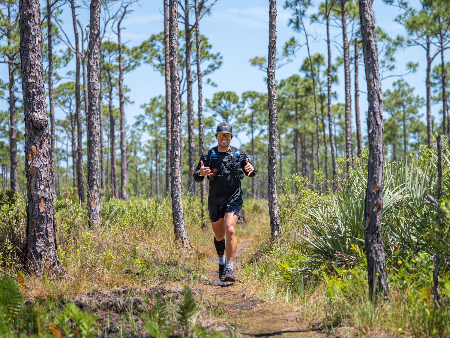 A trail runner makes their way through a scenic pine forest path on a sunny day in Florida.