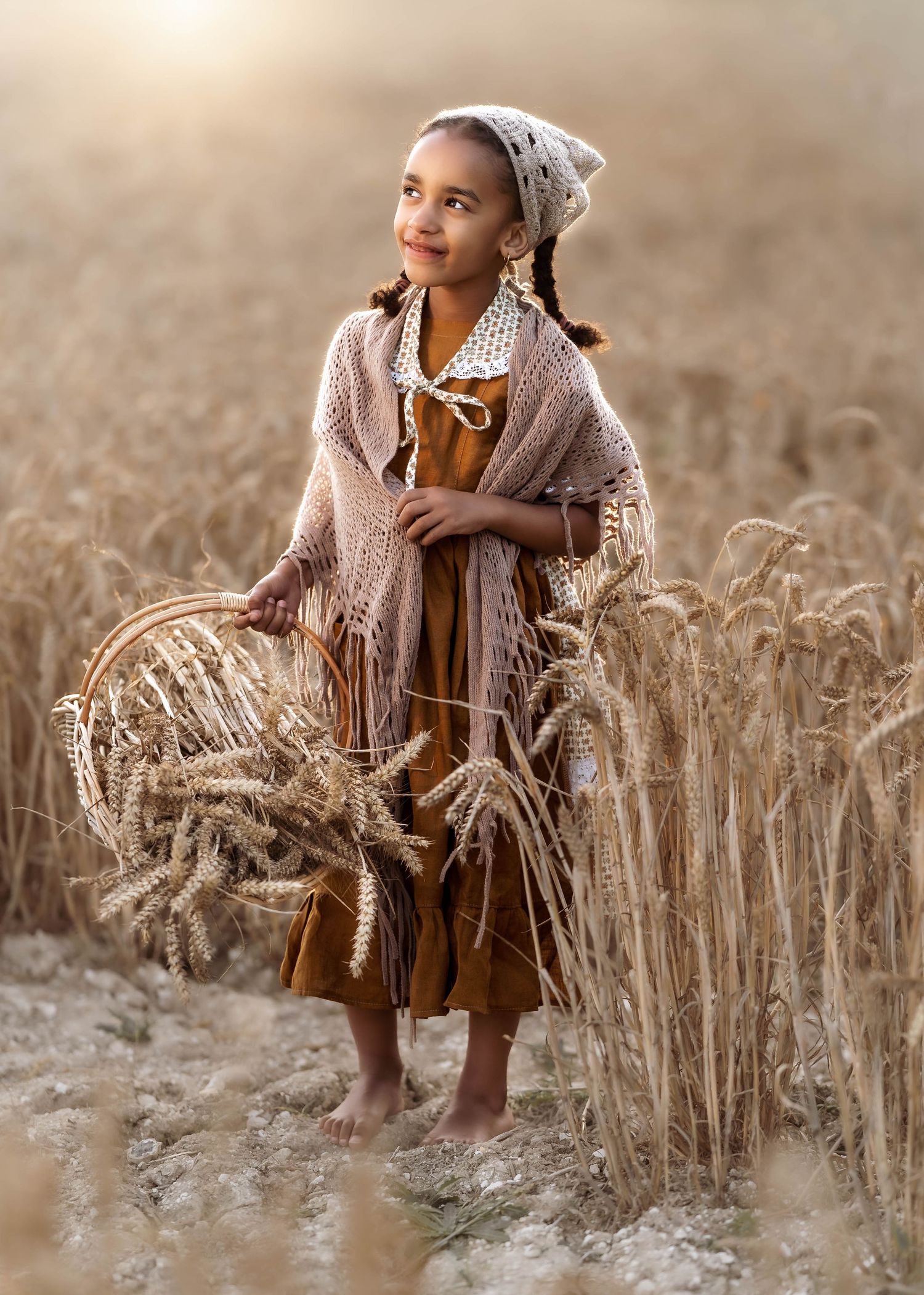 Dreamy portrait in wheat field wearing vintage dress and shawl during golden hour.