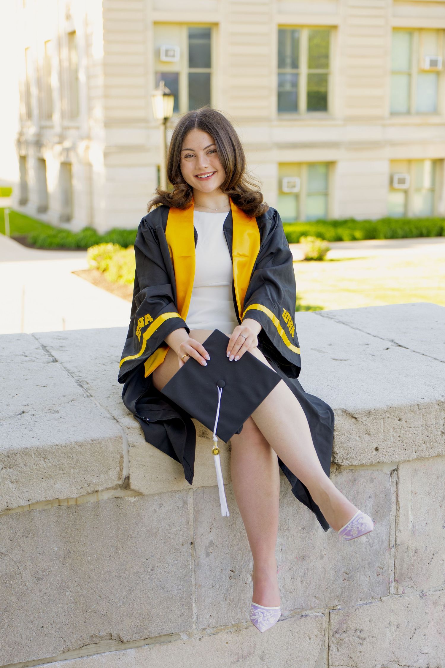 A woman throwing her graduation cap into the air on the steps of the old capitol in Iowa City