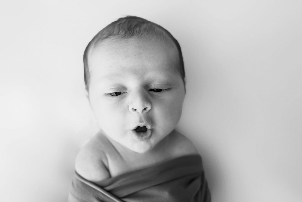 Black and white portrait series of sleeping newborn with gentle lighting.