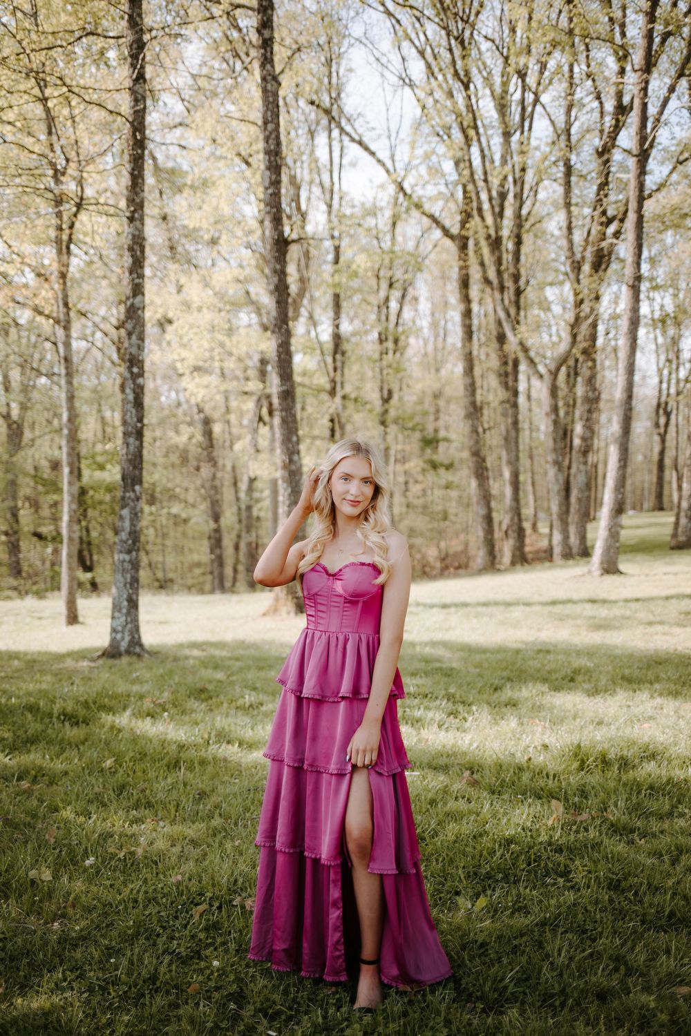 Young blonde woman in a pink tiered formal gown posing gracefully in a spring woodland setting at the Templeton Library, Sewanee Tennessee
