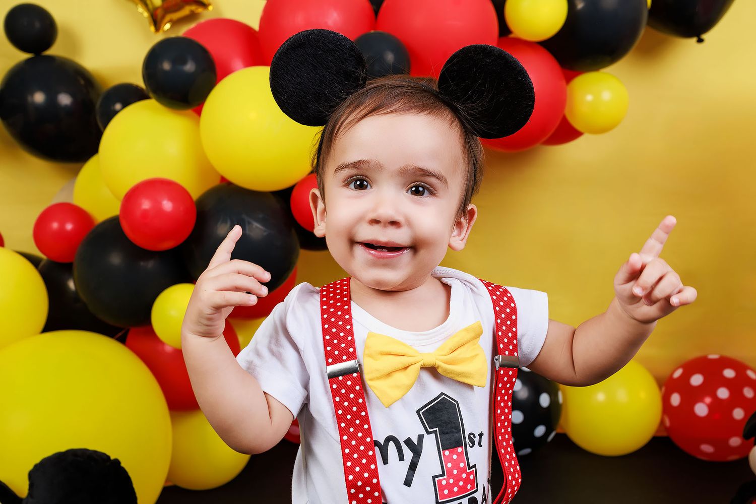 A festive Mickey Mouse themed party setup with red, yellow and black balloon decorations.