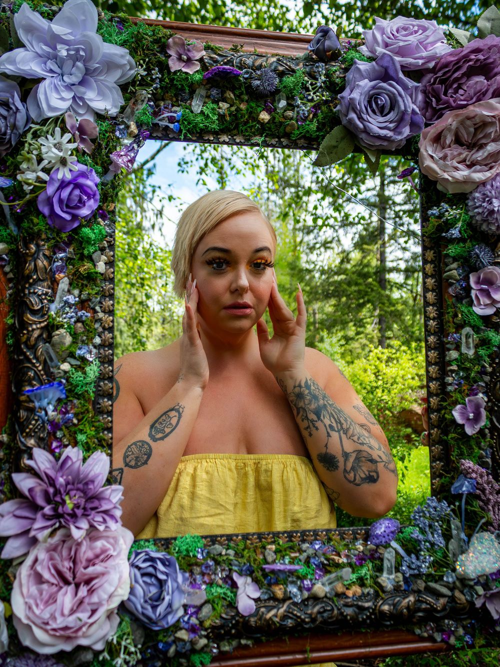 A decorative frame adorned with purple and pink flowers showcases a portrait against a natural green backdrop.